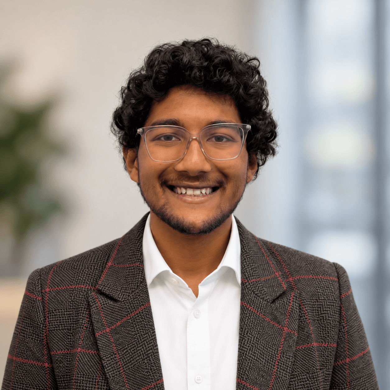 Elliot Saha wearing glasses and a brown checked jacket